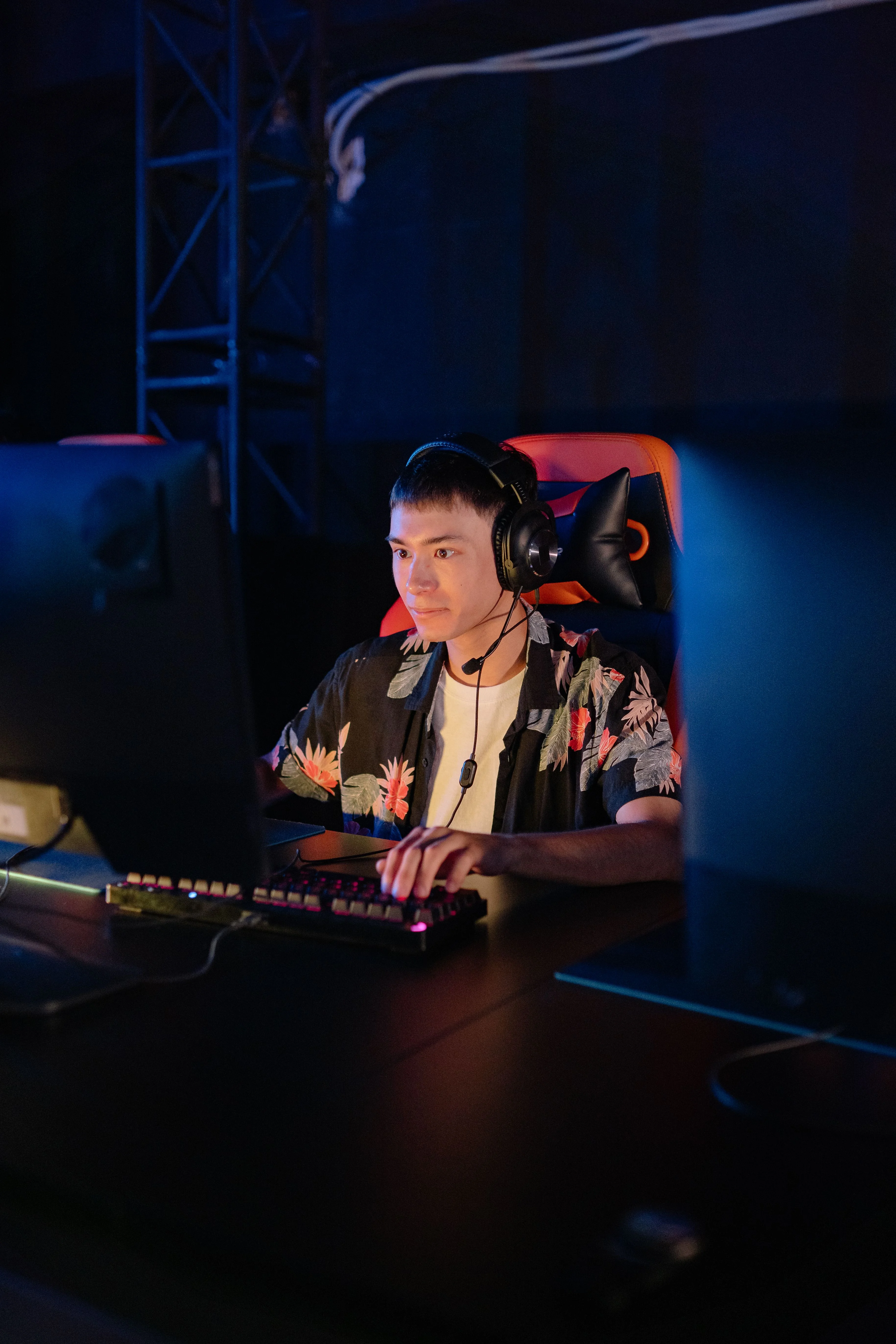 A man wearing a headset at a computer in a dim room, a former OnlyFans chatbot handler who messaged fans while posing as the model